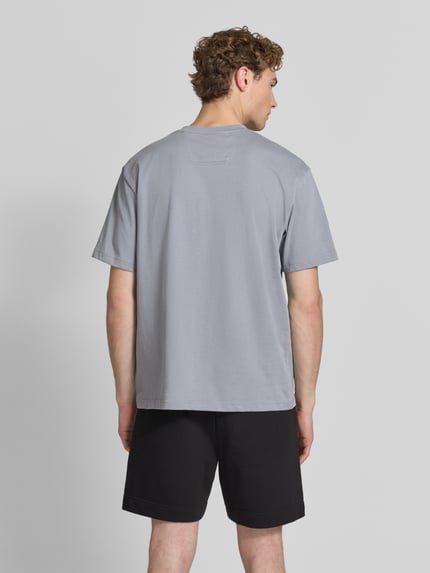 Mężczyzna nosi szary męski t-shirt Relaxed Fit T-Shirt aus reiner Baumwolle Modell 'TEE 10' von BOSS Green, prosta faktura, Ganzkörperansicht Rückansicht.