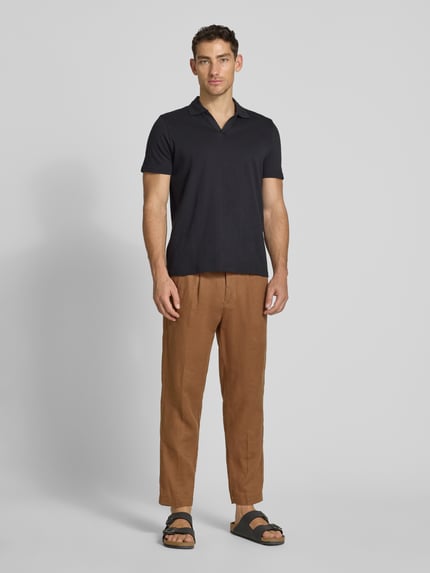 Męski model nosi Slim Fit Poloshirt mit V-Ausschnitt od MCNEAL, czarna bawełna, krój slim fit, przód, zdjęcie całej sylwetki.