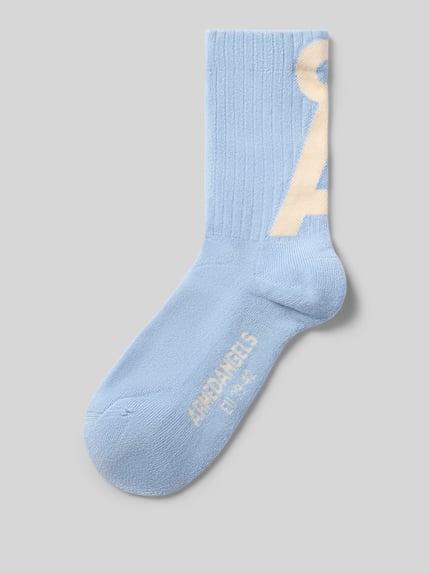 Produktfoto, hellblaue Socken aus Baumwoll-Mix Modell 'SAAMUS' von ARMEDANGELS mit Logo-Schriftzug, Feinstrick, elastischer gerippter Bund, verstärkte Ferse, unifarbene Optik auf grauem Hintergrund.