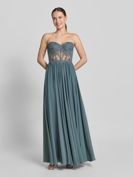 Frauenmodel trägt Abendkleid mit Spitze und Gehschlitz von Mascara in Blau, Herz-Ausschnitt, Strassbesatz, semitransparent, tailliert, Ganzkörperansicht von vorne.