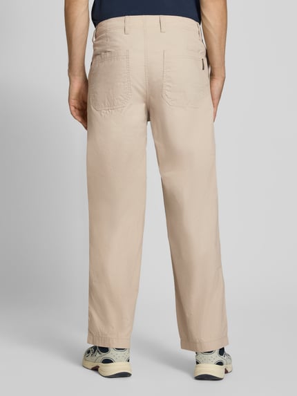 Męski model nosi jasnobeżowe spodnie z szerokimi nogawkami z czystej bawełny Wide Fit Hose aus reiner Baumwolle Modell 'Bill' von JACK & JONES, wpuszczane kieszenie i kieszenie z tyłu, zapięcie na guzik i zamek błyskawiczny, Szerokość w rozmiarze 32/32: 44 cm, Długość wewnętrzna nogawki w rozmiarze 32/32: 77 cm, widok całej sylwetki od tyłu.