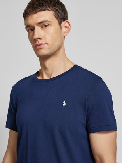 Männermodel trägt T-Shirt mit Logo-Stitching von Polo Ralph Lauren in Dunkelblau aus reiner Baumwolle, Nahaufnahme Oberkörper.