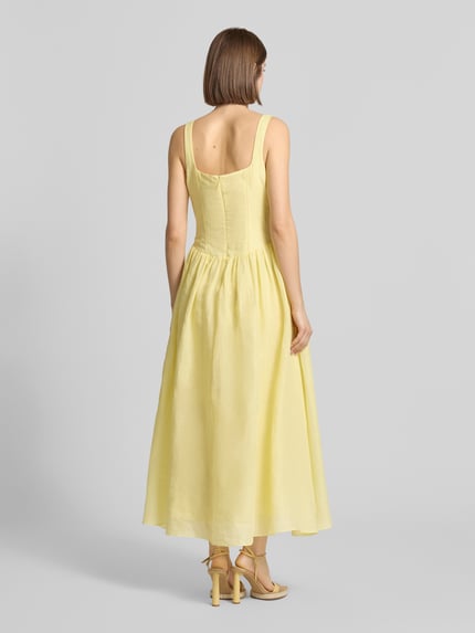 Frauenmodel trägt Midikleid aus Ramie Modell 'LAWRENCE SCOOP' von Bardot in Hellgelb, A-Linie, Karree-Ausschnitt, Rückenansicht, Rückseitiger Reißverschluss, Rückenlänge bei Größe 36: 114 cm, Brustweite: 43 cm, fließende Textur. Ganzkörperansicht Rückansicht.