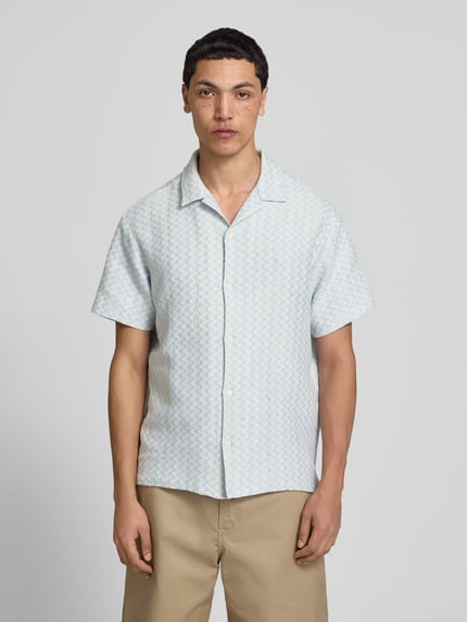 Männermodel trägt Regular Fit Freizeithemd im Allover-Look Modell 'MONTAUK' von Jack & Jones, Material-Mix mit Baumwoll-Anteil, Reverskragen, Knopfleiste, hellblau-gelbes Muster, glatte Textur, Ganzkörperansicht von vorne.