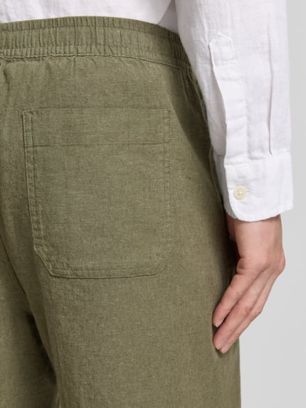 Männermodel trägt Leinenshorts mit elastischem Bund von GAP im Leinen-Baumwoll-Mix, Loose-Fit, Gesäßtasche, Nahaufnahme Rückansicht.