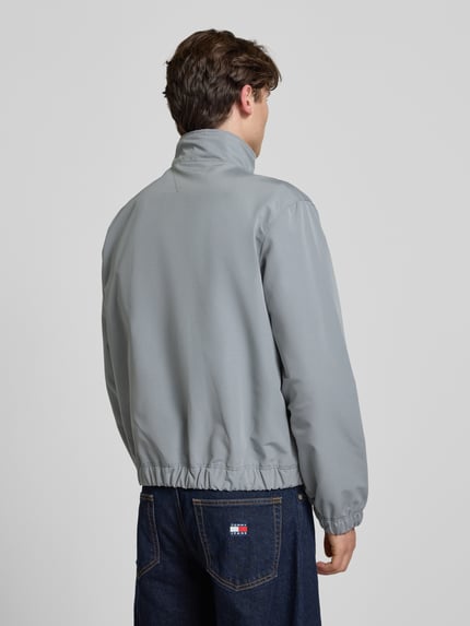 Männermodel trägt Regular Fit Bomberjacke mit Label Stitching von Tommy Jeans in Optik: Unifarben, Ganzkörperansicht Rückansicht.