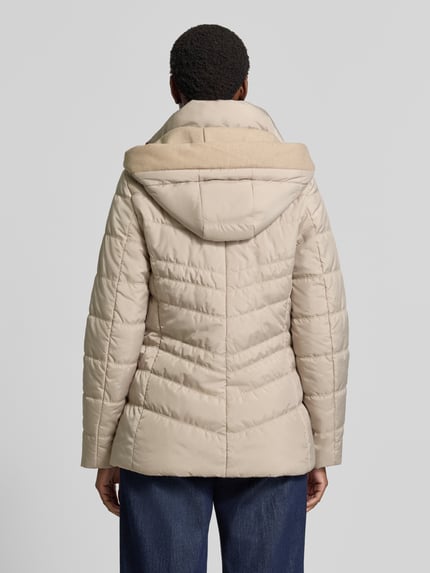 Frauenmodel trägt Jacke in Stepp-Optik mit Kapuze von FUCHS SCHMITT, beżowy kolor, taliowany krój, wpuszczane kieszenie z zamkiem błyskawicznym, kaptur, stójka z ociepleniem, długość tyłu w rozmiarze 36: 74 cm, szerokość ramion: 40 cm, szerokość klatki piersiowej: 48 cm, długość rękawów: 64 cm, widok całej sylwetki z tyłu