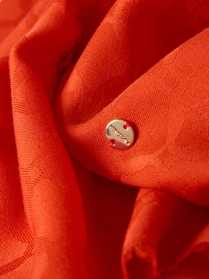 Productfoto, Schal mit Label-Detail van Marc Cain, puur scheerwol, rechthoekige vorm, label-accent, rafels, oranje textuur, detailopname.