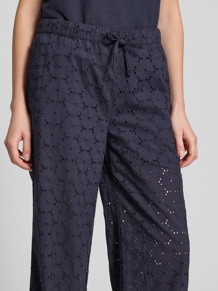 Frauenmodel trägt Stoffhose mit Lochstickerei von Christian Berg Woman aus Reine Baumwolle in Navy, elastischer Bund, Nahaufnahme Oberkörper.