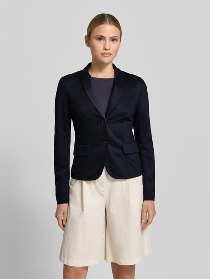 Frauenmodel trägt Slim Fit Blazer aus Viskose-Mix von Marc Cain in Dunkelblau mit Reverskragen, 2-Knopfverschluss, Pattentaschen, Ganzkörperansicht von vorne, Rückenlänge 56 cm, Brustweite 23 cm, Ärmellänge 63 cm, Größe 36.