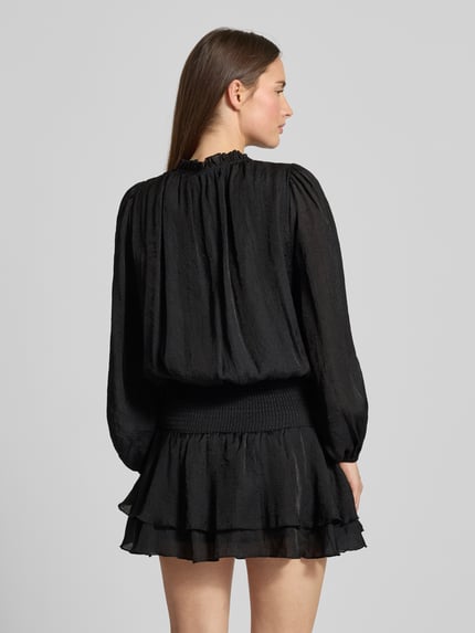 Frauenmodel trägt Cocktailkleid im Stufen-Look Modell 'Bari' von Neo Noir aus schwarzem Chiffon, taillierter Schnitt, Minikleid, Ganzkörperansicht Rückansicht.