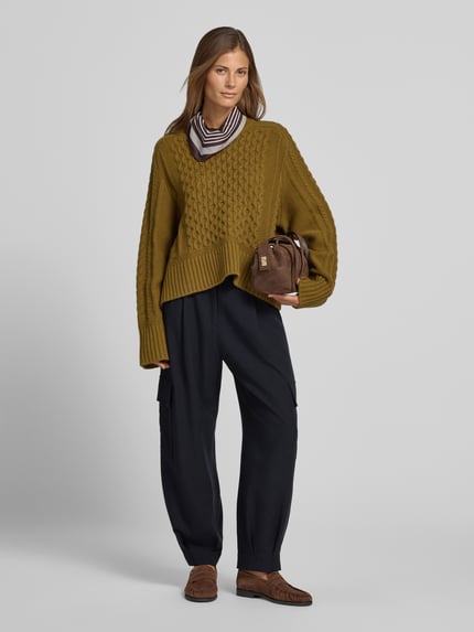 Frauenmodel trägt Strickpullover mit Zopfmuster von Style Icon Collection in Olivgrün, gerippte Abschlüsse, lockere Passform, Ganzkörperansicht von vorne.