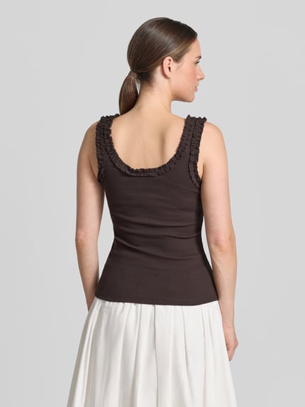 Frauenmodel trägt Trägertop mit Rundhalsausschnitt und Rüschen von Copenhagen Muse, Baumwoll-Elasthan-Mix, Slim-Fit, Ripp-Optik, Rückenlänge 38 cm, Ganzkörperansicht Rückansicht.