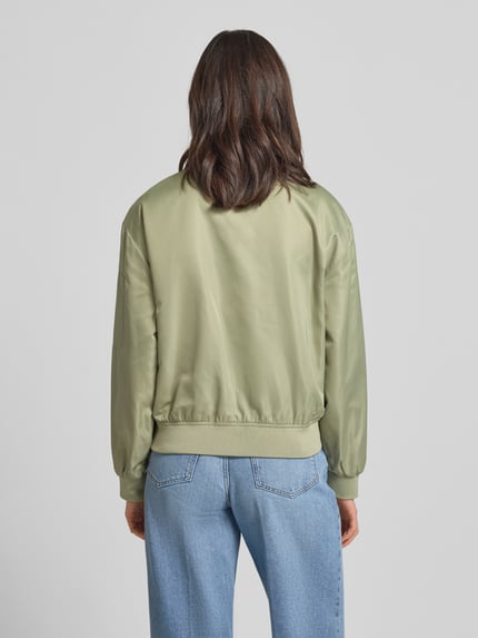 Frauenmodel trägt Regular Fit Bomberjacke mit College-Kragen von s.Oliver RED LABEL in Optik: Unifarben, Satin Materialverarbeitung, Ganzkörperansicht Rückansicht.