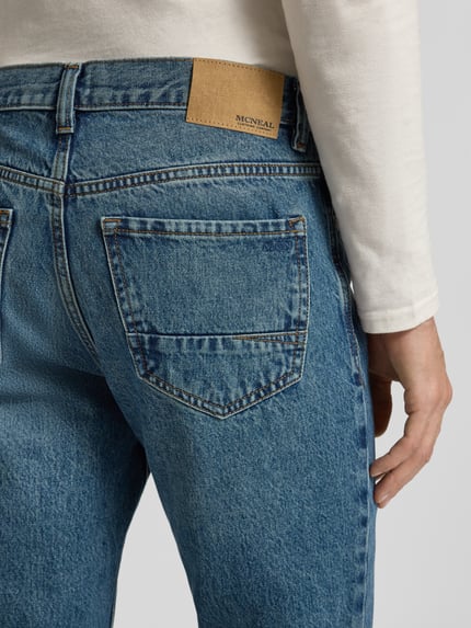 Männermodel trägt Loose Fit Jeans im 5-Pocket-Design von MCNEAL aus reiner Baumwolle in mittelblau, Detailaufnahme Gesäßbereich.