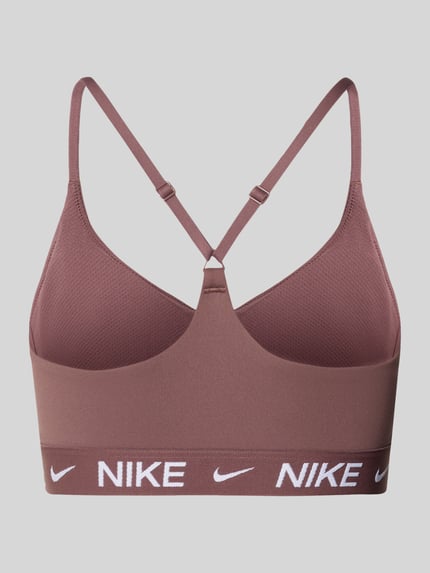 Vrouwenmodel draagt Bustier met Label-Details en verstelbare bandjes van NIKE TRAINING in bruin met nauwsluitende pasvorm en elastische band, Ganzkörperansicht Rückansicht