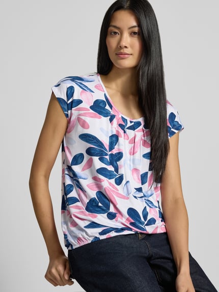 Vrouwenmodel draagt blouse met korte mouwen uit mix van viscose en elastaan Modell 'Minou' van ZABAIONE, los model, ronde hals, plooien, elastische band, met korte mouwen, ruglengte bij maat S 56 cm, meerkleurig, nahaufnahme bovenlichaam.