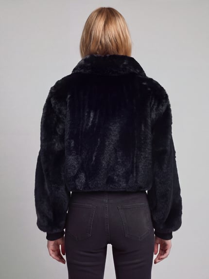 Frauenmodel trägt Webpelzjacke mit Logo-Detail Modell 'Fabi-1' von HUGO, unifarben, strukturierte Oberfläche, oversized, cropped, Ganzkörperansicht Rückansicht.