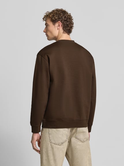 Mannenmodel draagt slim fit pullover uit pure katoen 'TOM' van Selected, effen bruin, grof geweven textuur, hele lichaam achteraanzicht. Heren sweatshirt