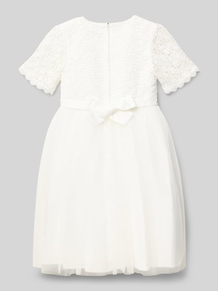 Mädchen trägt Knielanges Kleid mit Rundhalsausschnitt von DANAMADE, taillierter Schnitt, blickdichtes Unterkleid, Rückansicht Ganzkörperansicht.