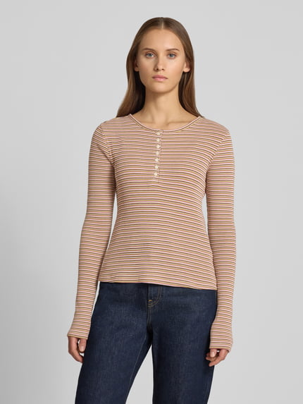 Frauenmodel trägt Slim Fit Langarmshirt aus reiner Baumwolle von REVIEW in Beige mit feinen Streifen, Rundhalsausschnitt, Knopfleiste, Ganzkörperansicht von vorne.