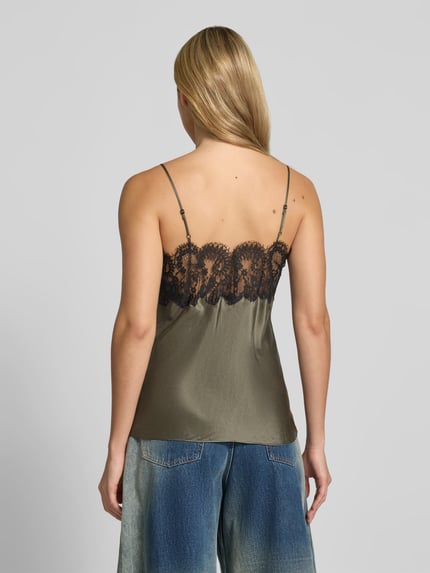 Frauenmodel trägt Top aus reiner Seide von Iro, olivgrün mit schwarzem Spitzenbesatz, ärmellos, Satinstruktur, Ganzkörperansicht Rückansicht.
