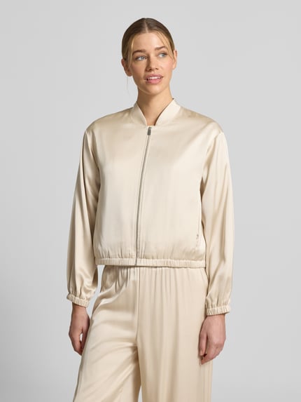 Frauenmodel trägt Blouson mit Stehkragen und Reißverschluss von Comma aus Material-Mix mit Viskose-Anteil, Regular-Fit, beige, Nahaufnahme Oberkörper.
