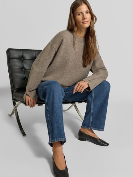 Frauenmodel trägt Regular Fit Pullover aus Woll-Mix mit Kaschmir-Anteil von MYON, beige Strick-Optik, Kombi mit Jeans, Ganzkörperansicht von vorne.