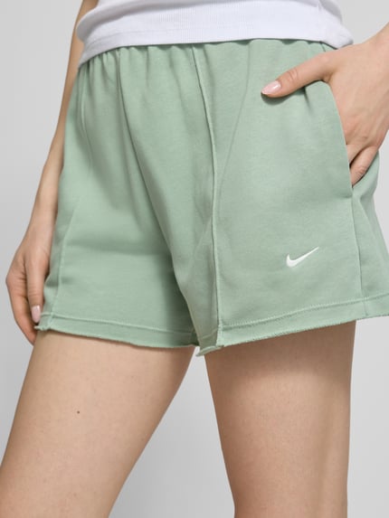 Frauenmodel trägt Regular Fit Shorts mit Tunnelzug von Nike aus Baumwoll-Mix mit Logo-Stitching in Mintgrün, Nahaufnahme Oberschenkel.