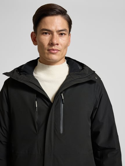 Männermodel trägt schwarzen Parka mit Kapuze und Ärmelriegeln Modell 'BAKERHILL' von Icepeak, Material-Mix, Nahaufnahme Oberkörper.