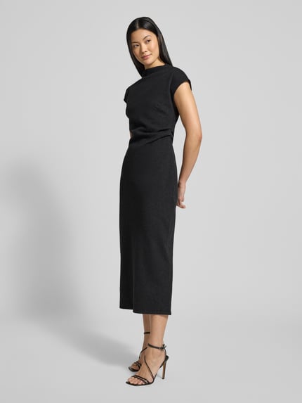 Frauenmodel trägt schwarzes Midikleid mit Stehkragen Modell 'Dominique' von GUIDO MARIA KRETSCHMER, tailliert, seitliche Ganzkörperansicht. Baumwoll-Mix, Raffungen, Nahtreißverschluss, Rückenlänge 121 cm, Brustweite 44 cm, Ärmellänge 22 cm.