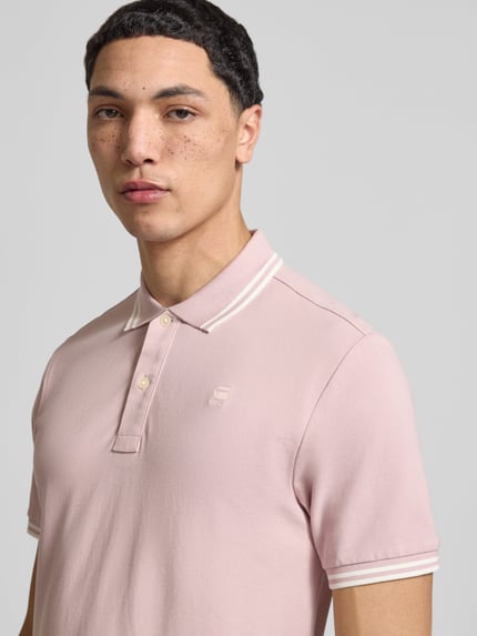 Männermodel trägt Slim Fit Poloshirt mit Logo-Stitching Modell 'Dunda' von G-Star Raw in Rosa, elastischer Baumwoll-Mix, Nahaufnahme Oberkörper.