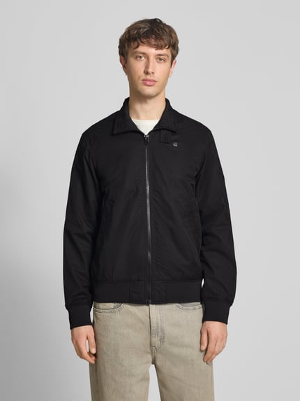 Männermodel trägt schwarze Jacke mit Stehkragen und Reißverschluss von G-Star Raw, Baumwoll-Mix, Regular Fit, Ganzkörperansicht von vorne.