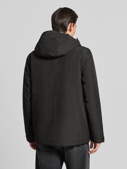 Männermodel trägt Regular Fit Jacke mit Kapuze Modell 'Adam' von Didriksons in Schwarz, glatte Struktur, Ganzkörperansicht Rückansicht. Rückenlänge bei Größe M: 79 cm, Schulterbreite: 46 cm, Brustweite: 58 cm, Ärmellänge: 73 cm.