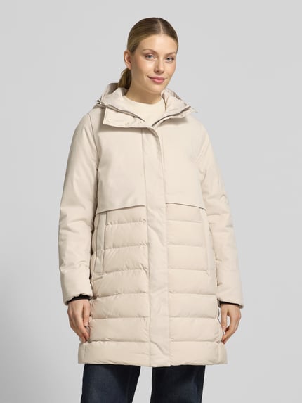 Frauenmodel trägt Regular Fit Steppmantel mit Eingrifftaschen von camel active in hellem Beige mit Steppnähten, verdecktem Reißverschluss, Kapuze, Ganzkörperansicht von vorne. Rückenlänge 93 cm, Schulterbreite 43 cm, Brustweite 56 cm, Ärmellänge 66 cm.