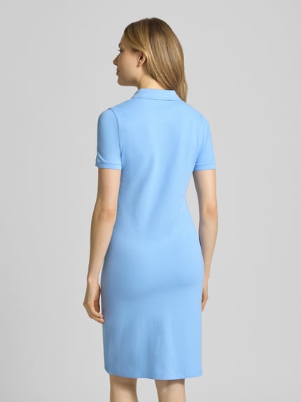Modelka kobieca nosi 'Knielanges Polokleid mit Label-Stitching' od Gant, mieszanka bawełny i elastanu, prosty krój, długość do kolan, wyhaftowane logo, listwa guzikowa, długość tyłu w rozmiarze S: 95 cm, szerokość w rozmiarze S: 41 cm, długość rękawów w rozmiarze S: 20 cm, jasnoniebieski, gładka tekstura, pełny widok z tyłu.