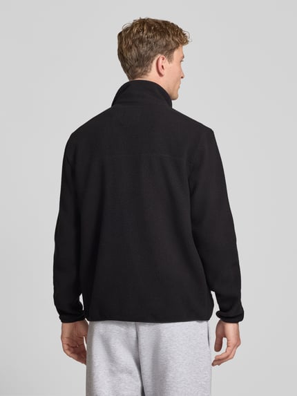 Mężczyzna model nosi czarną kurtkę z polaru o kroju regular fit ze stójką Regular Fit Fleecejacke mit Stehkragen Modell 'JASON' von ONLY & SONS, Ganzkörperansicht Rückansicht.