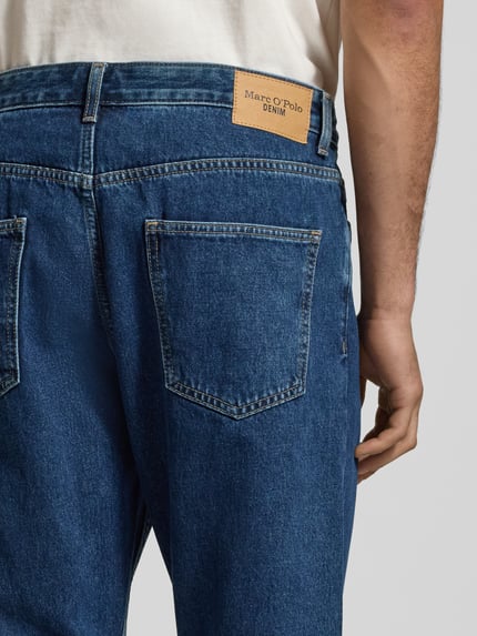 Männermodel trägt Tapered Fit Jeans aus pure katoen, model 'RUNNA' van Marc O'Polo Denim, blauwe denim, label patch, 5-pocket, detailopname achterzijde.