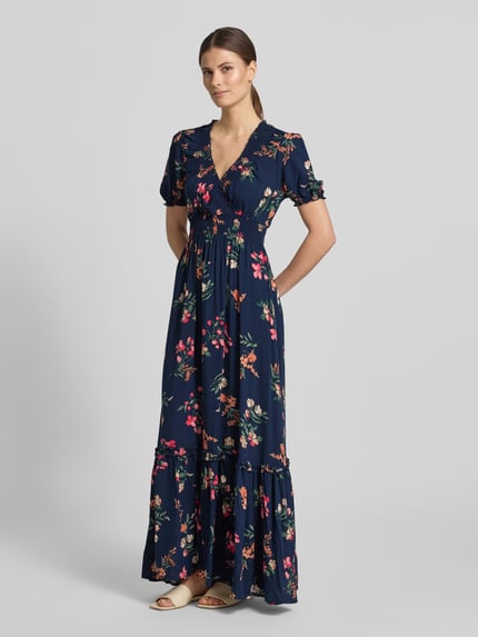 Vrouwenmodel draagt Regular Fit maxi-jurk uit zuiver viscose met V-hals van Apricot, bloemen all-over print, getailleerd, korte mouw, plooien, elastische mouwboorden, ruglengte maat S 134 cm, borstwijdte 45 cm, mouwlengte 25 cm, geheel vooraanzicht.