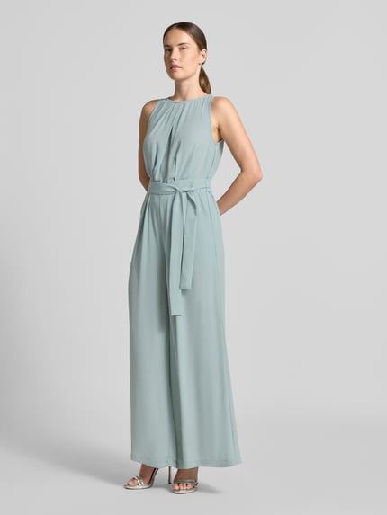 Modelka nosi kombinezon 'Jumpsuit mit rückseitigem V-Ausschnitt' od Zero, taliowany krój, okrągły dekolt, marszczenia, wiązany pasek, dekolt w serek na plecach, wiązanie z tyłu, długość tyłu w rozmiarze 36: 38 cm, szerokość w rozmiarze 36: 42 cm, całkowita długość w rozmiarze 36: 150 cm, długość wewnętrzna nogawki w rozmiarze 36: 73 cm, jasnoniebieski, gładka tekstura, widok całej sylwetki z przodu.