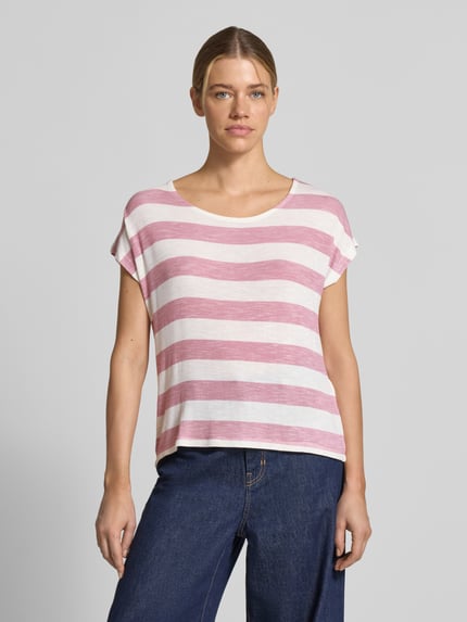 Frauenmodel trägt Boxy Fit T-Shirt aus Viskose-Mix Modell 'WIDE STRIPE' von Vero Moda mit Optik:Allover-Muster, Streifenmuster in Rosa und Weiß, Rundhals, Kurzarm, Rumpfabschluss: Asymmetrisch, Feinstrick. Ganzkörperansicht von vorne.