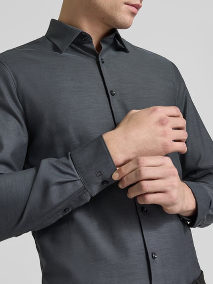 Männermodel trägt Slim Fit Businesshemd mit Kentkragen von OLYMP, melierte Optik, feines Webmuster, Nahaufnahme Oberkörper.