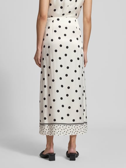 Vrouwenmodel draagt maxirok uit zuiver viscose Model 'Alba' van Ted Baker, los model, witte stof met zwarte stippen, totale lengte maat 36: 95 cm, bandwijdte maat 36: 38 cm, sierstrik, dames maxirok, geheel aanzicht rugzijde.