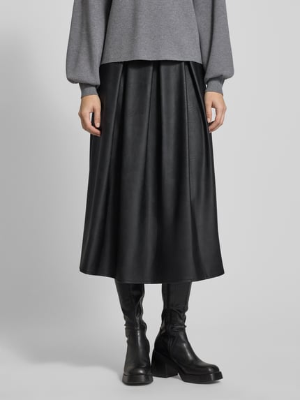Frauenmodel trägt schwarzen Midirock mit elastischem Bund von ZABAIONE in Leder-Optik, lockerer Schnitt, Nahaufnahme Unterkörper.