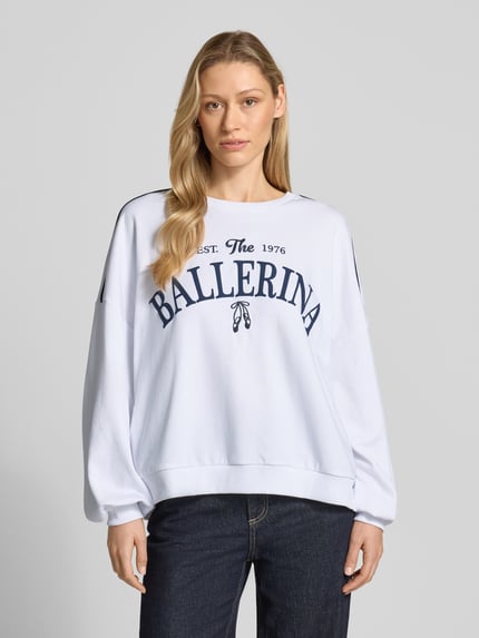 Frauenmodel trägt Oversized Sweatshirt aus Baumwoll-Mix Modell 'JAMIE' von Vero Moda, weiß, blauer Print, Kontraststreifen, Nahaufnahme Oberkörper.