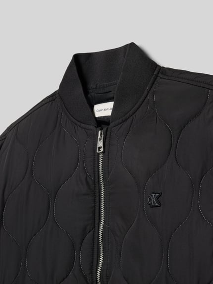 Produktfoto, Regular Fit Steppjacke mit Logo-Patch Modell 'Quilted' von Calvin Klein Jeans in schwarzer Stepp-Optik mit Stehkragen und elastischen Abschlüssen, Nahaufnahme Oberkörper, Rückenlänge 53 cm, Schulterbreite 45 cm, Ärmellänge 56 cm