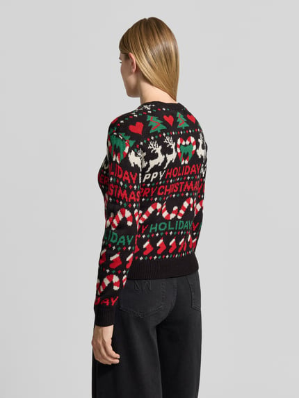 Frauenmodel trägt Pullover mit Weihnachtsmotiv-Frontprint von VERO MODA, mehrfarbig, Strickoptik, Ganzkörperansicht Rückansicht.