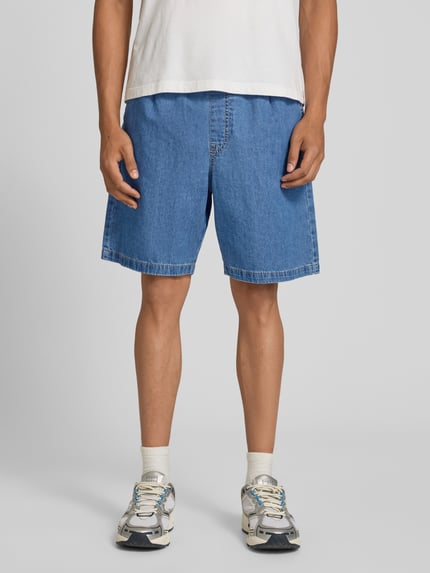 Männermodel trägt Shorts mit elastischem Bund und Kordelzug Modell 'TONY' von Jack & Jones aus reiner Baumwolle, Straight Fit, mittleres Blau, Ganzkörperansicht von vorne.