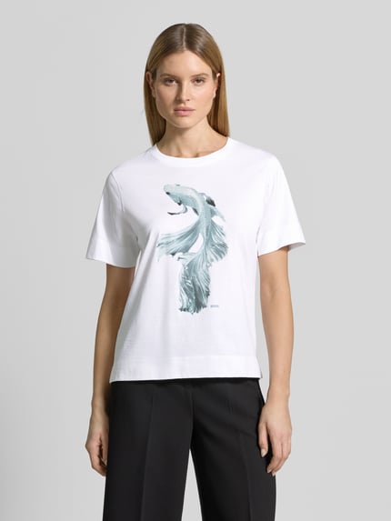 Modelka kobieca ma na sobie damski t-shirt Regular Fit T-Shirt aus reiner Baumwolle Modell 'ELPHA' von BOSS, biały, nadruk z motywem, okrągły dekolt, bawełniany dżersej, przód, Ganzkörperansicht von vorne.