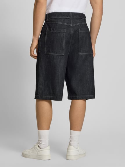 Männermodel trägt extra Baggy Fit Herren Bermudas Modell 'LLOYD' von Jack & Jones aus Reine Baumwolle mit Eingrifftaschen, Ganzkörperansicht Rückansicht.
